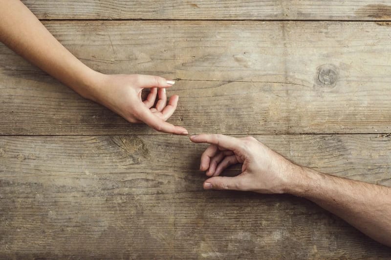 Párkapcsolati problémák kezelése life és mindfulness coachinggal - Egymás fele nyúló férfi és női kéz, ahogy egymást próbálják elérni.